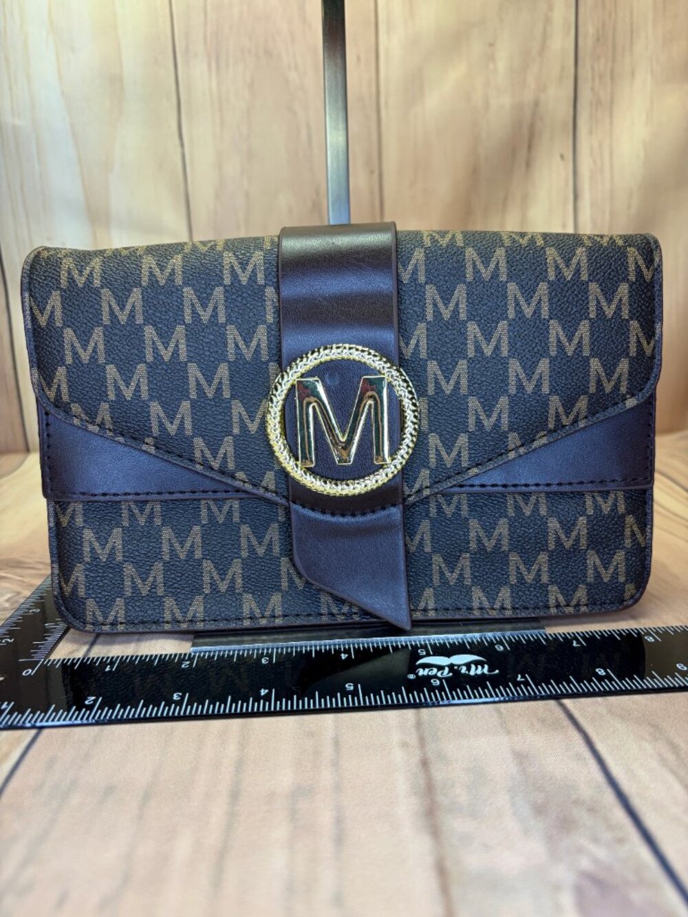 Brown monogram-print structured crossbody handbag featuring an all-over “M”
